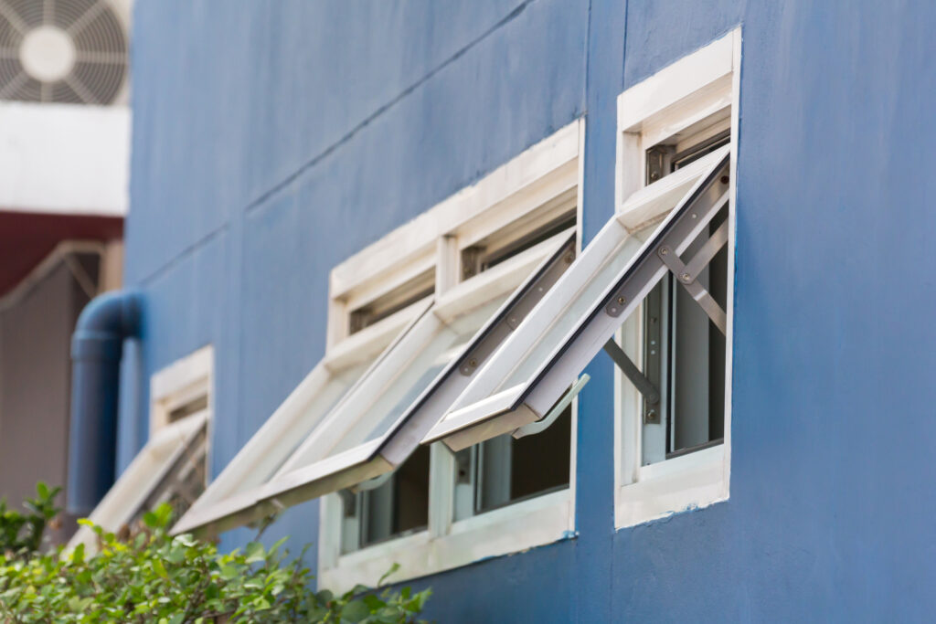 Open aluminum framed awning windows on a blue wall