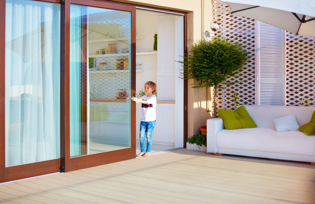 happy young boy opening the sliding door on a patio area at home